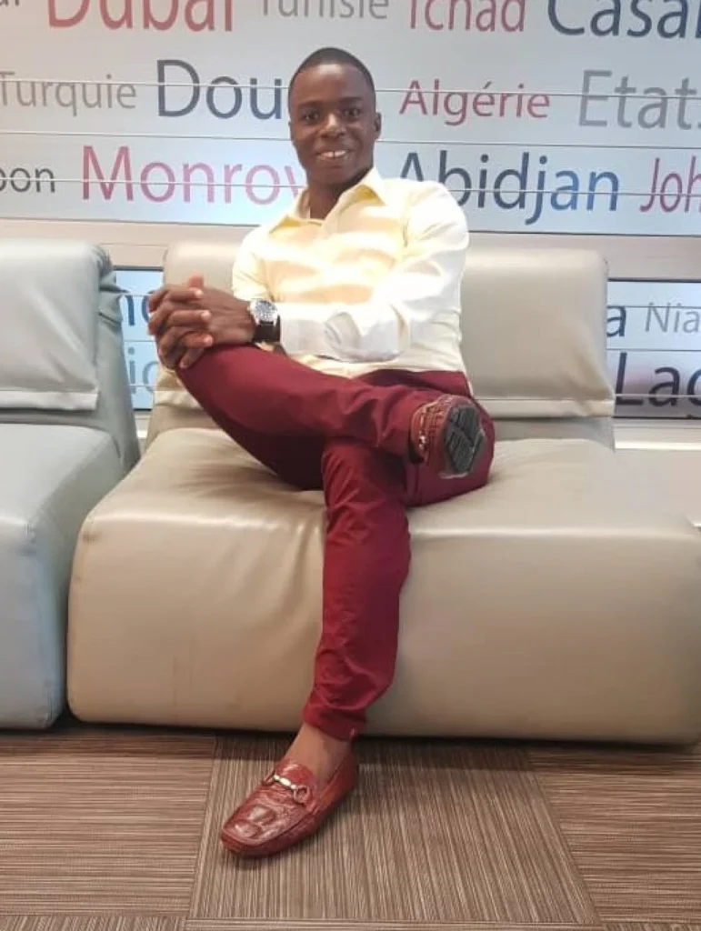 Platinum Star Houffoue Yao Hyacinthe Shares His Direct Selling Success Tips 3 Houffoue Yao Hyacinthe sitting on a couch smiling in a yellow shirt and red pants