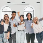 Group of young men and women in office giving thumbs up