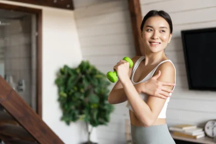 Woman exercising with a small dumbbell, reaping the benefits of a plant-based diet, which includes easing climate change effects