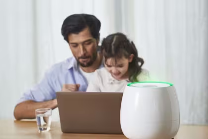 A father and his daughter sit at a table with a laptop, while HomePure Zayn ensures safe and clean indoor air
