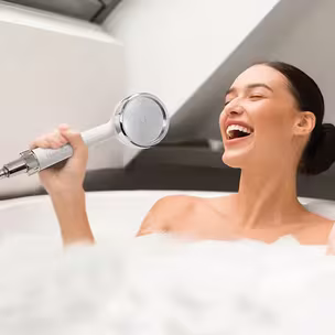 Lady singing in the bathtub, HomePure Rayn in hand.