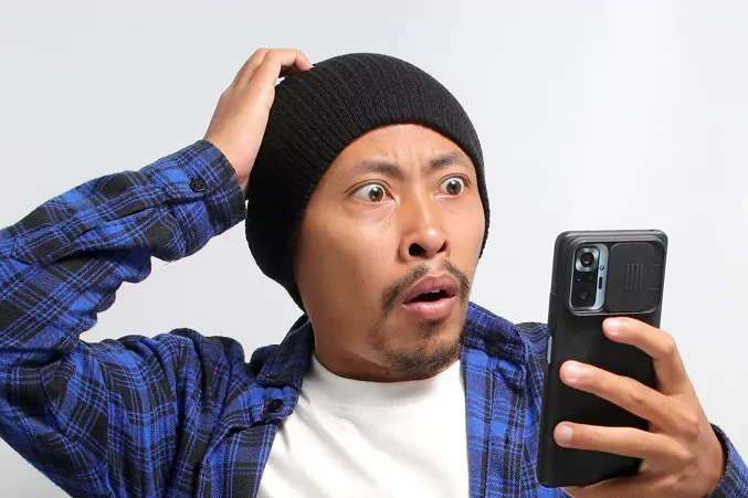 Qnet Vs Phishing Scams 2 man looking at his phone shocked