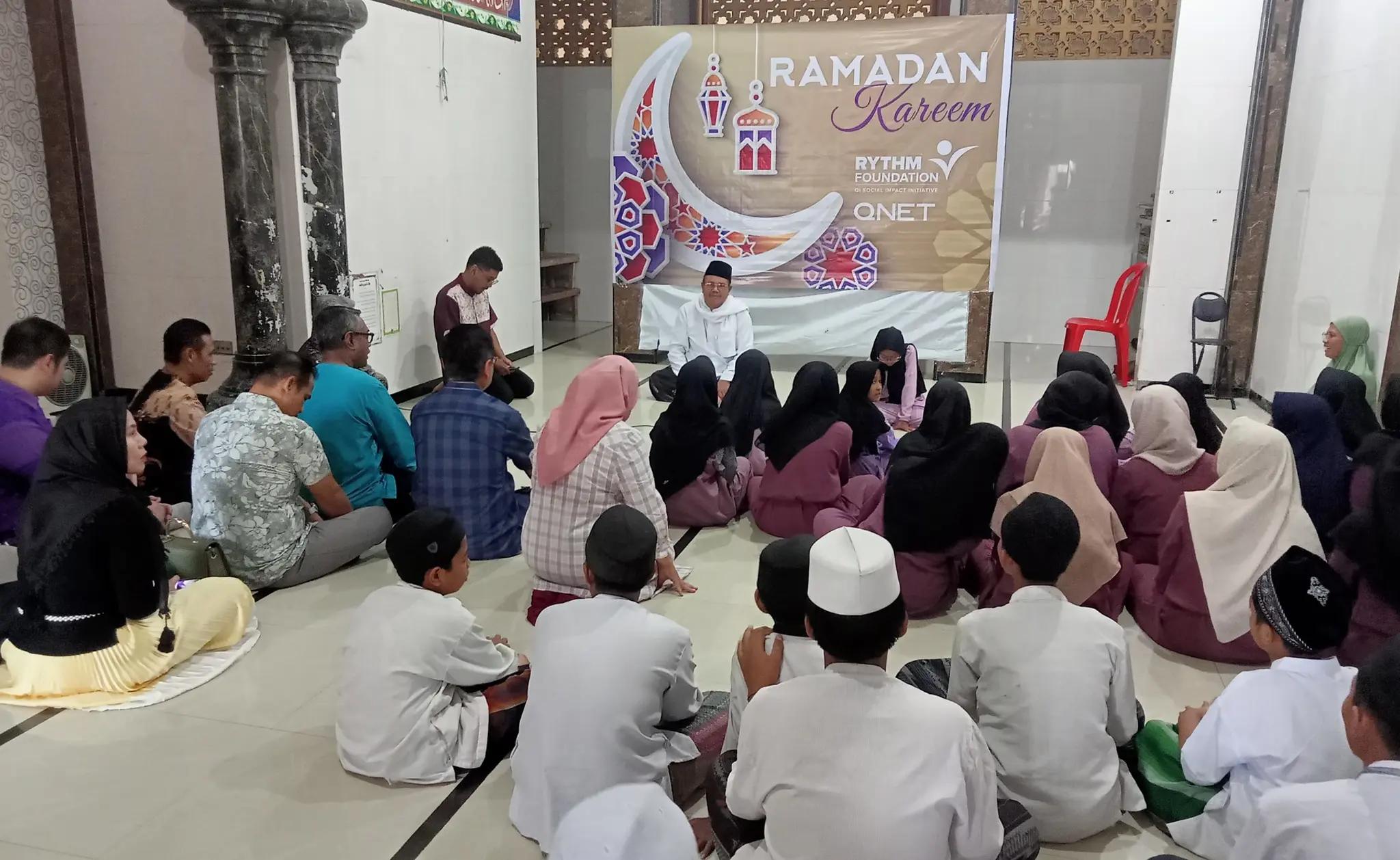 People sitting on the floor while reflecting during a QNET Ramadan initiative in Indonesia