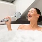 Lady in bathtub using HomePure Rayn shower head as a microphone