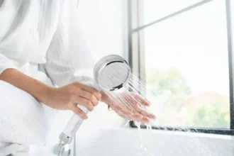 Hand holding a HomePure Rayn shower head with flowing water